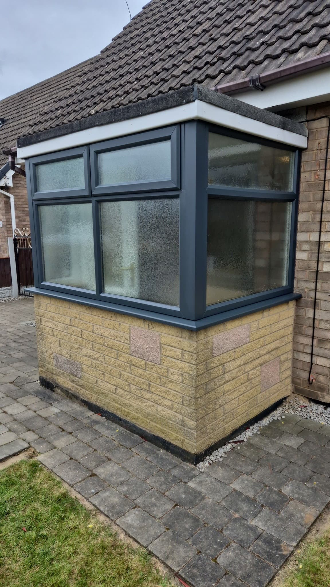 Dark grey UPVC window frames on a brick bay window after spraying.
